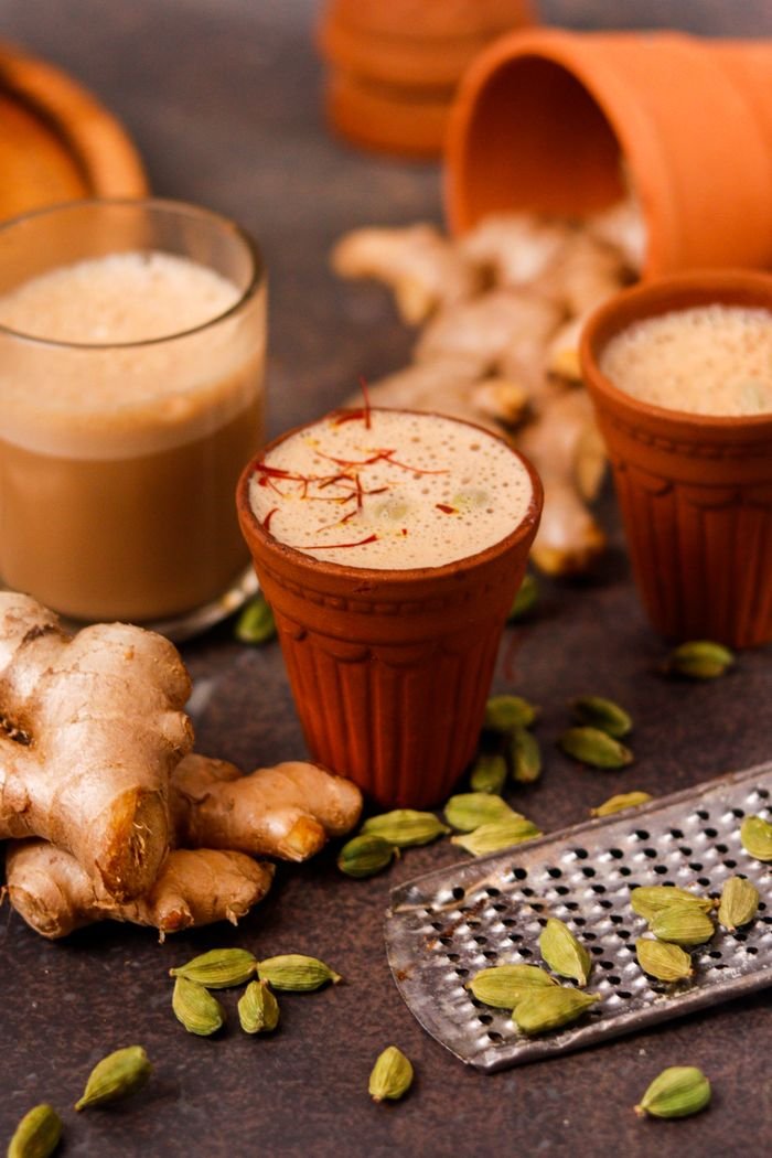 services-01 Close-up of masala chai in clay cups surrounded by ginger and cardamom for a rustic look.