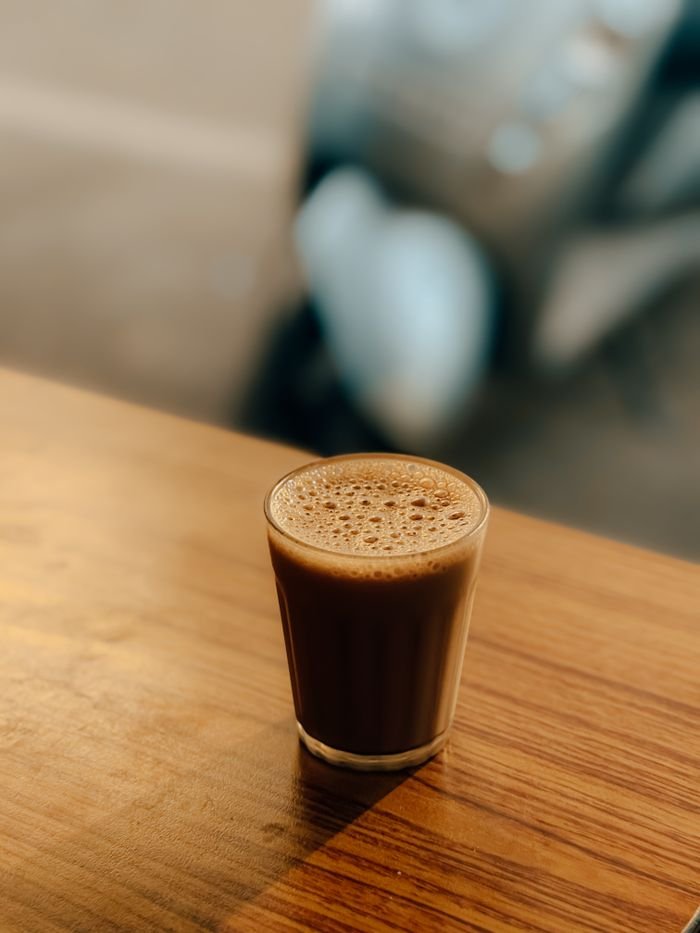 who-we-are Authentic Indian chai tea in a glass on a wooden table, evoking traditional tea culture.