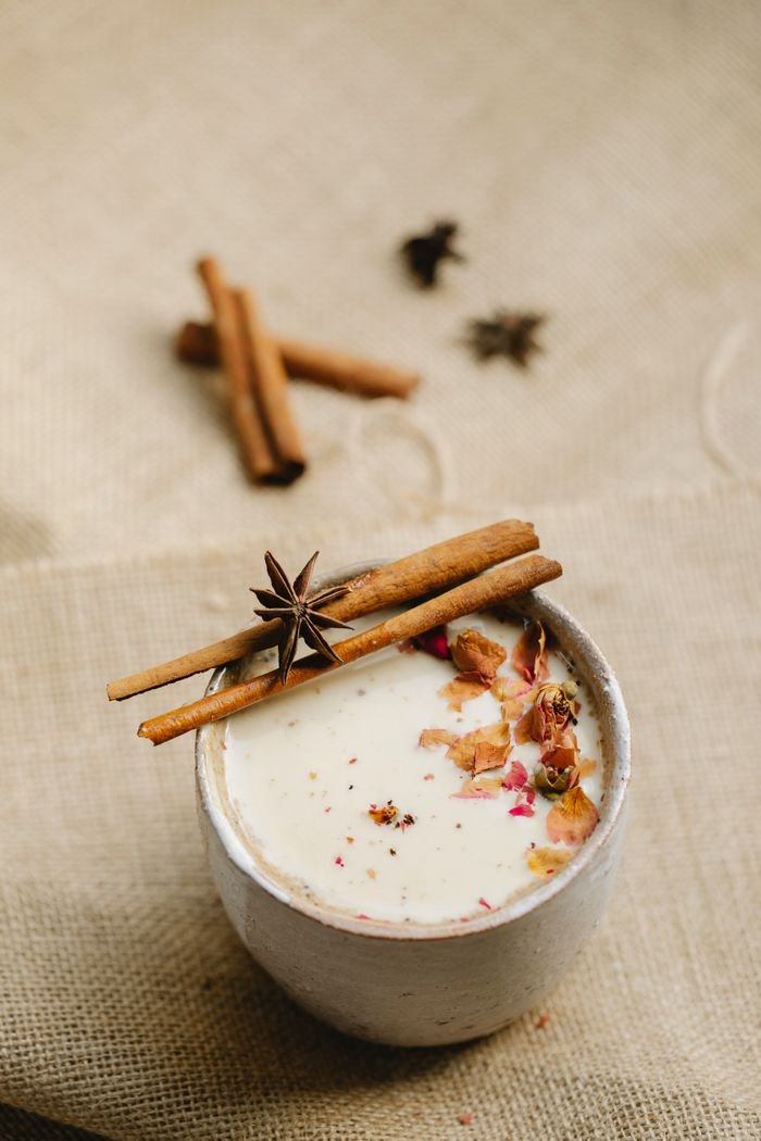 about-us From above composition of tasty homemade chai tea served in ceramic mug with star anise on sticks of cinnamon and other spices placed on gray linen tablecloth